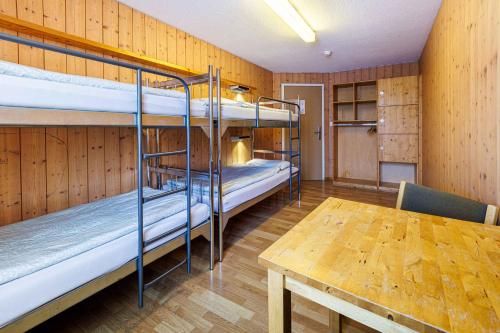 英格堡Engelberg Youth Hostel的客房设有两张双层床和一张桌子。