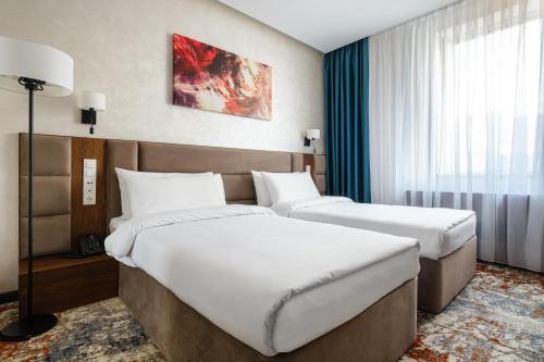 阿拉木图Grand Mildom Hotel的酒店客房设有两张床和窗户。
