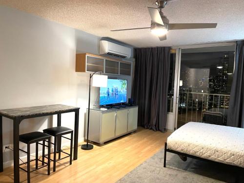 檀香山Marine Surf的一间卧室配有一张床、一台电视和一张桌子