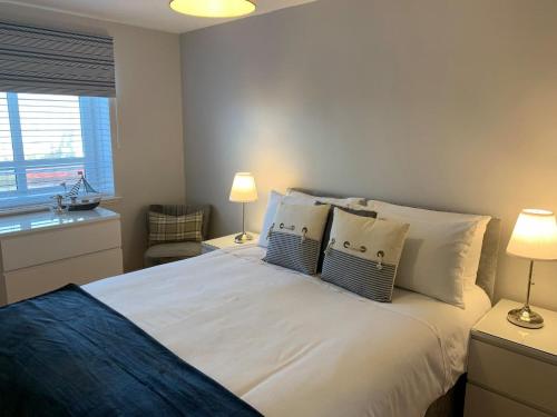 艾尔Kintyre Apartment的卧室配有带枕头的白色床和窗户。