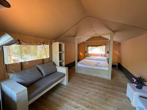 Echarri-AranazCAMPING ETXARRI的带沙发的客厅和帐篷内的1张床
