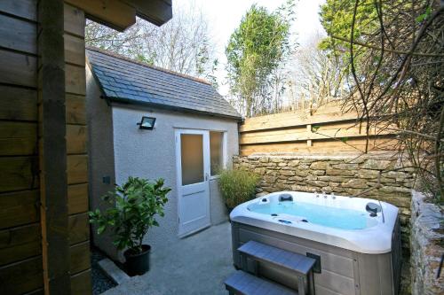 普里茅斯Yealm Cabin Self Catering Log Cabin in Devon with Hot Tub的建筑旁带按摩浴缸的后院
