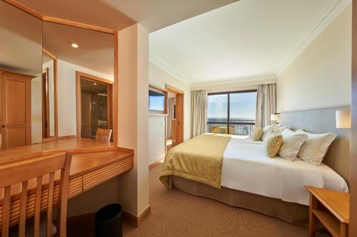 丰沙尔梅尔波尔图湾酒店&度假村的一间卧室配有一张床、一张书桌和一个窗户。