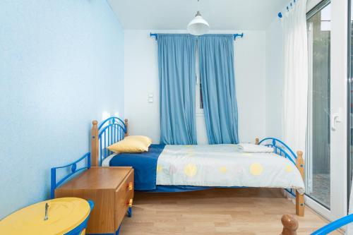 拉夫蒂港Coral Cottage House by A&D Properties的一间小卧室,配有一张带蓝色窗帘的床