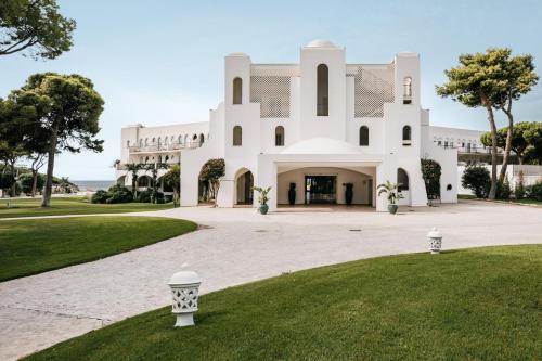 维拉西米乌斯卡波博伊法肯斯特诺度假酒店的一座白色的大建筑,有草地庭院