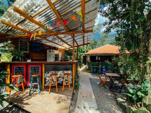 阿布拉奥Mambembe Hostel - Ilha Grande的庭院设有带椅子和桌子的酒吧