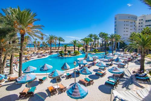 苏塞Riadh Palms- Resort & Spa的享有带椅子和遮阳伞的度假村游泳池的空中景致
