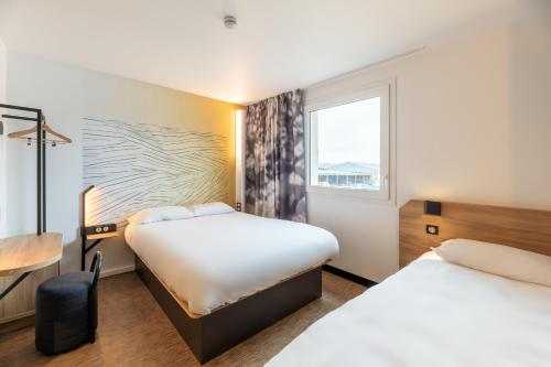 维里埃特B&B HOTELS Bourg-en-Bresse Viriat的酒店客房设有两张床和窗户。