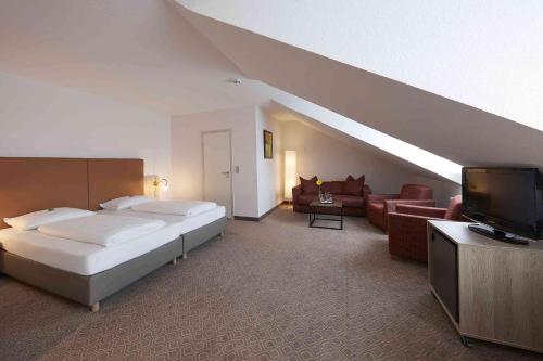 基尔基尔GHOTEL生活酒店的一间卧室配有一张床、一张沙发和一台电视。