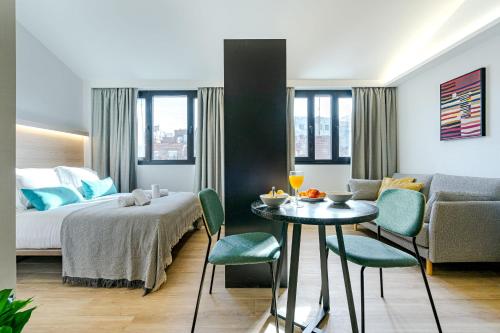 马德里Feelathome Ventas Suites的酒店客房带一张床、一张桌子和椅子