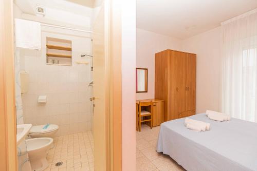里米尼Hotel Arlino的浴室设有床、卫生间和水槽。
