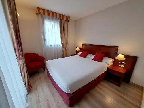 安道尔城Hotel Spa Termes Carlemany的酒店客房,配有一张床和一张红色椅子