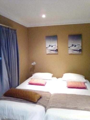 德班Mkhandi Self Catering的两张位于酒店客房的床,墙上挂有照片