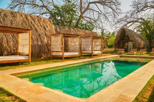 穆库拉岛Hotel Isla Mucura的一个带游泳池和茅草屋顶的度假胜地