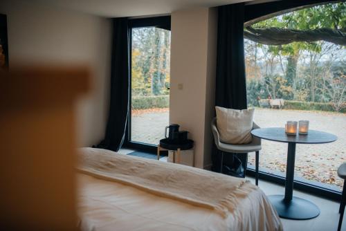 亨法尔Chambres d'hôtes Eucalyptus et Glycine的一间卧室配有一张床、一张桌子和一个窗户。
