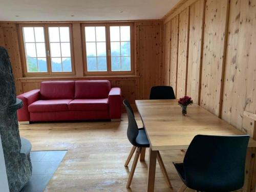 MonsteinNeuwertiges 2-Zi-Ferienchalet 55m2的客厅配有桌子和红色沙发