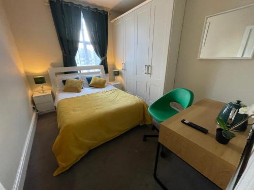 都柏林银鹰住宿加早餐旅馆的一间卧室配有一张带黄色床罩的床和一张书桌