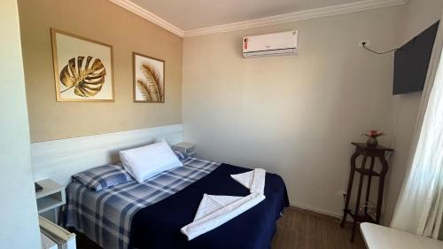 嘎林海斯港Suites Carioca的小房间,配有一张带蓝色毯子的床