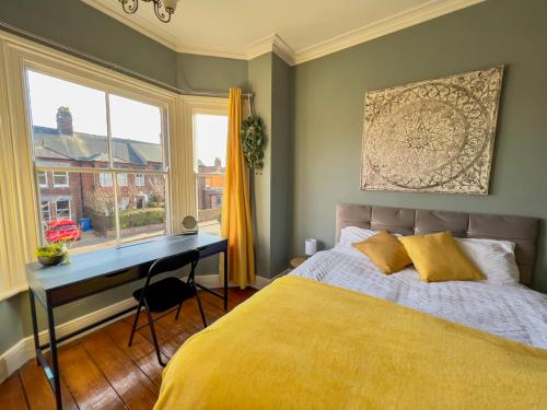 诺里奇Stylish 4 bed house with parking in central Norwich的一间卧室配有一张床、一张书桌和一个窗户。