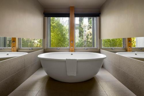 赫本温泉Mineral Springs Hotel Hepburn的大型浴室设有3个水槽和1个大浴缸。