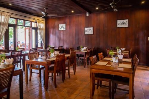 琅勃拉邦沙达酒店的餐厅拥有木墙和木桌及椅子