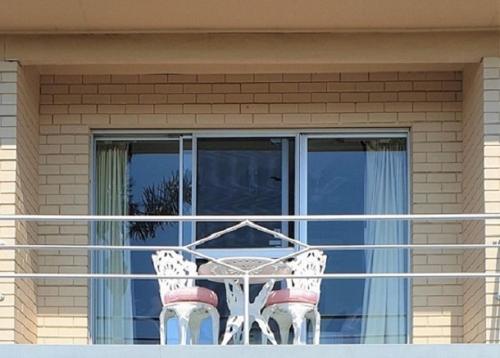 莫里莫科Mollymook Ocean View Motel Rewards Longer Stays -over 18s Only的窗户前的阳台配有桌椅