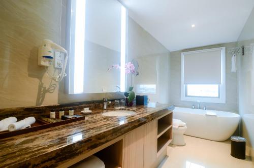 巨港艾克斯顿酒店的一间带水槽、浴缸和卫生间的浴室