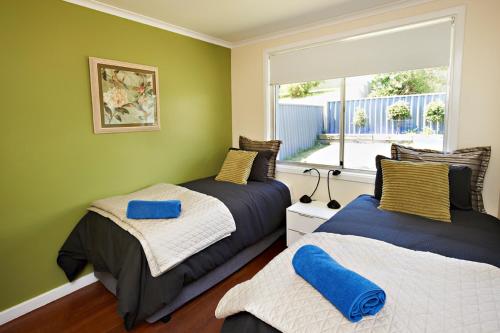 奥尔巴尼奥尔巴尼海港公寓别墅酒店的配有两张床的客房,设有绿色的墙壁和窗户