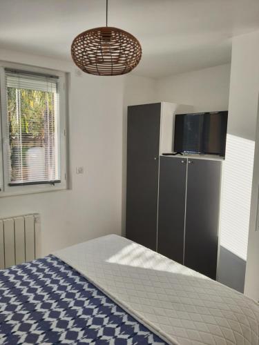 佩罗勒Appartement Pérols Centre的一间卧室配有一张床、一个橱柜和一台电视