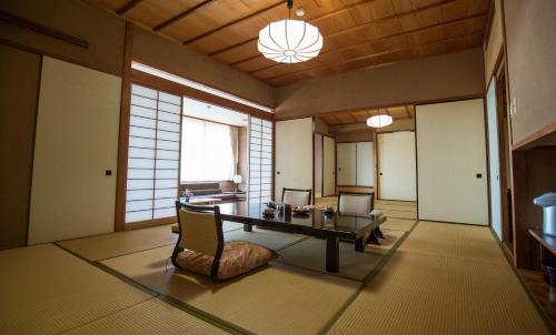 伊豆Sakahijiri gyokushoen的一间客房内配有桌椅的房间
