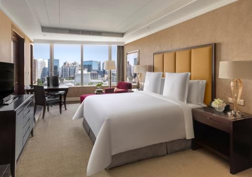 北京北京四季酒店的一间大卧室,配有一张白色的大床和一张书桌