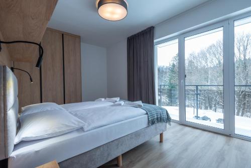 斯克拉斯卡波伦巴Apartamenty na Uroczysku的一间卧室设有一张床和一个大窗户