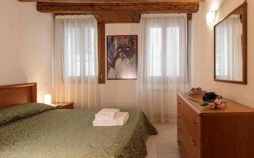 威尼斯佩里格里诺商业酒店的一间卧室设有绿色的床、梳妆台和窗户。