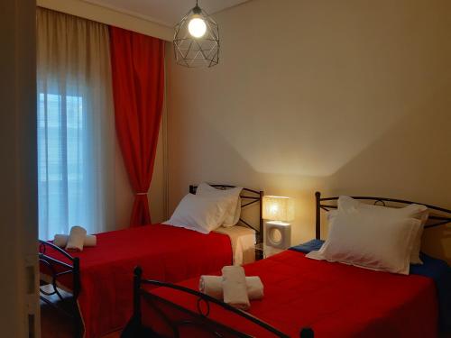 特里卡拉Elegante apartamento centrale的一间卧室设有两张带红色床单的床和窗户。