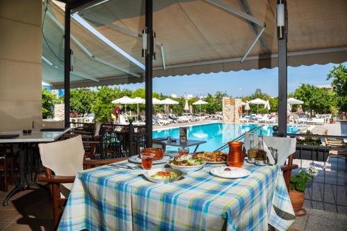 伊利索斯Ilyssion Holidays Hotel的游泳池旁的餐桌上放着食物