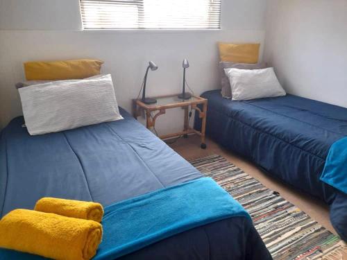 亨蒂斯湾Beachfront Selfcatering的一间设有两张蓝色的床和一张桌子的房间