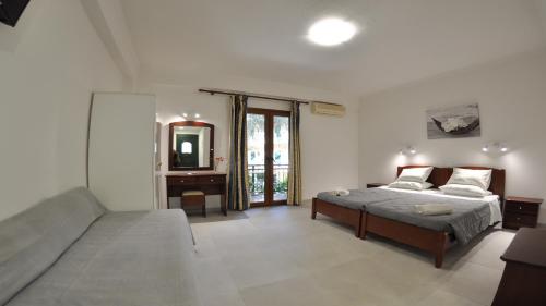 里亚帕德斯Villa Katerina Apartments的一间卧室配有一张床、一张沙发和一面镜子