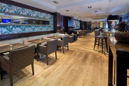 吉尔福德Mandolay Hotel Guildford的一间带桌椅的餐厅和一间酒吧