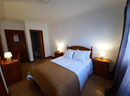 蓬塔德尔加达Hotel Insular的一间卧室配有一张大床和两盏灯