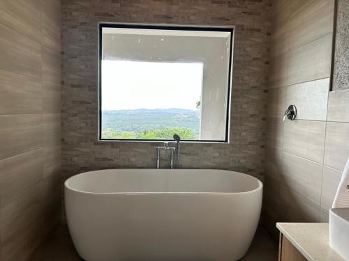 雾观Hazyview Accommodation, Bon Repose Cottages 3&4的带窗户的浴室内的白色浴缸