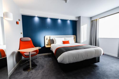 威根Holiday Inn Express - Wigan, an IHG Hotel的酒店客房,配有一张床和一张红色椅子