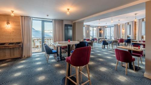 沃雅尼Madame Vacances Hotel Les Cimes的餐厅设有桌椅和大窗户。