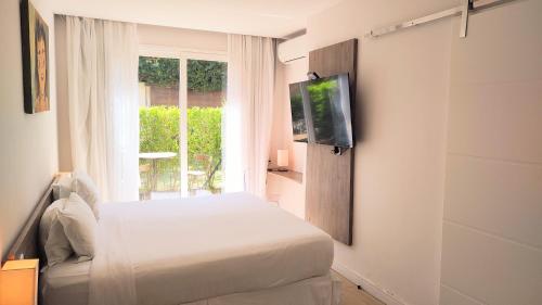 布希奥斯Parador Búzios Boutique Hotel的一间卧室设有一张床、一台电视和一个窗口。