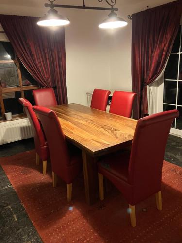 阿马Ridge Wood House的一张木桌,配有红色椅子