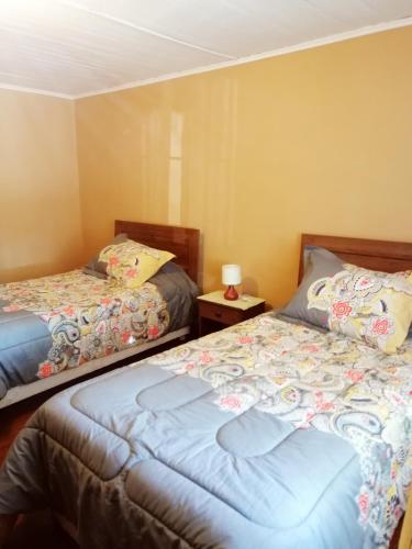 帕尼马维达Hostel Casa Descanso Natural的一间卧室设有两张床和一张桌子上的台灯。