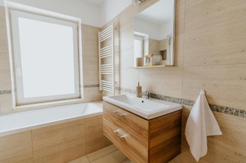 奥多尔黑塞库耶斯克Lotus Apartman II的一间带水槽和浴缸的浴室以及窗户。
