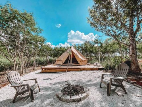 哈莱伊瓦Cute Off Grid Glampsite with WiFi- 5 min from Haleiwa Town的田野上的两把椅子和一个帐篷