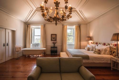 塞图巴尔Hotel Casa Palmela - Small Luxury Hotels of The World, Hotel & Villas的一间卧室配有一张床、一张沙发和一个吊灯。