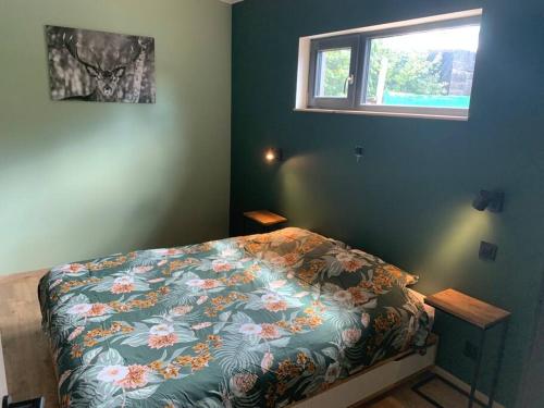 胡法利兹Le cabanon的一间卧室配有一张带花卉床罩的床和窗户。