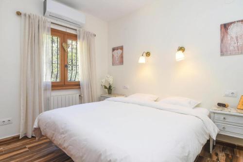 库姆布勒德尔索尔Villa Encinas的白色的卧室设有一张大床和一个窗户